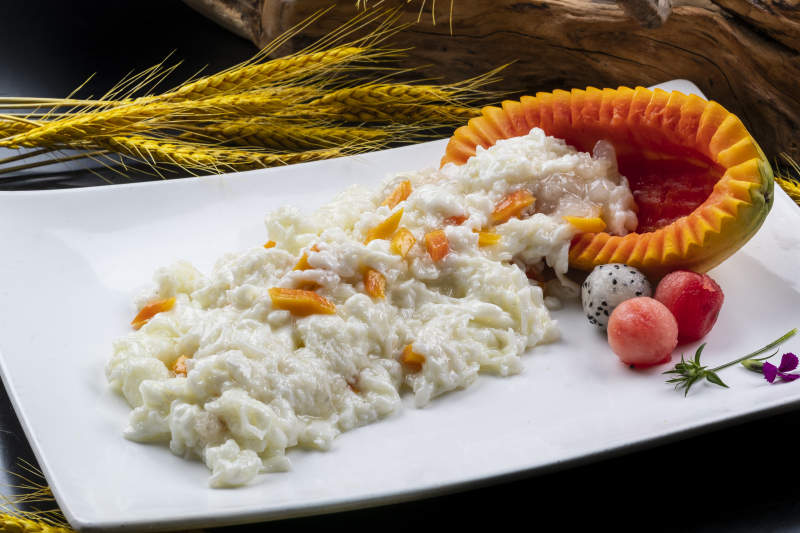 长方形瓷盘装的木瓜芙蓉蛋摆放在黑色背景上图片