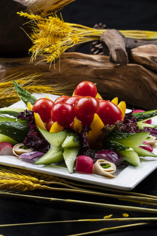 方形瓷盘装的田园大拌菜摆放在黑色背景上图片