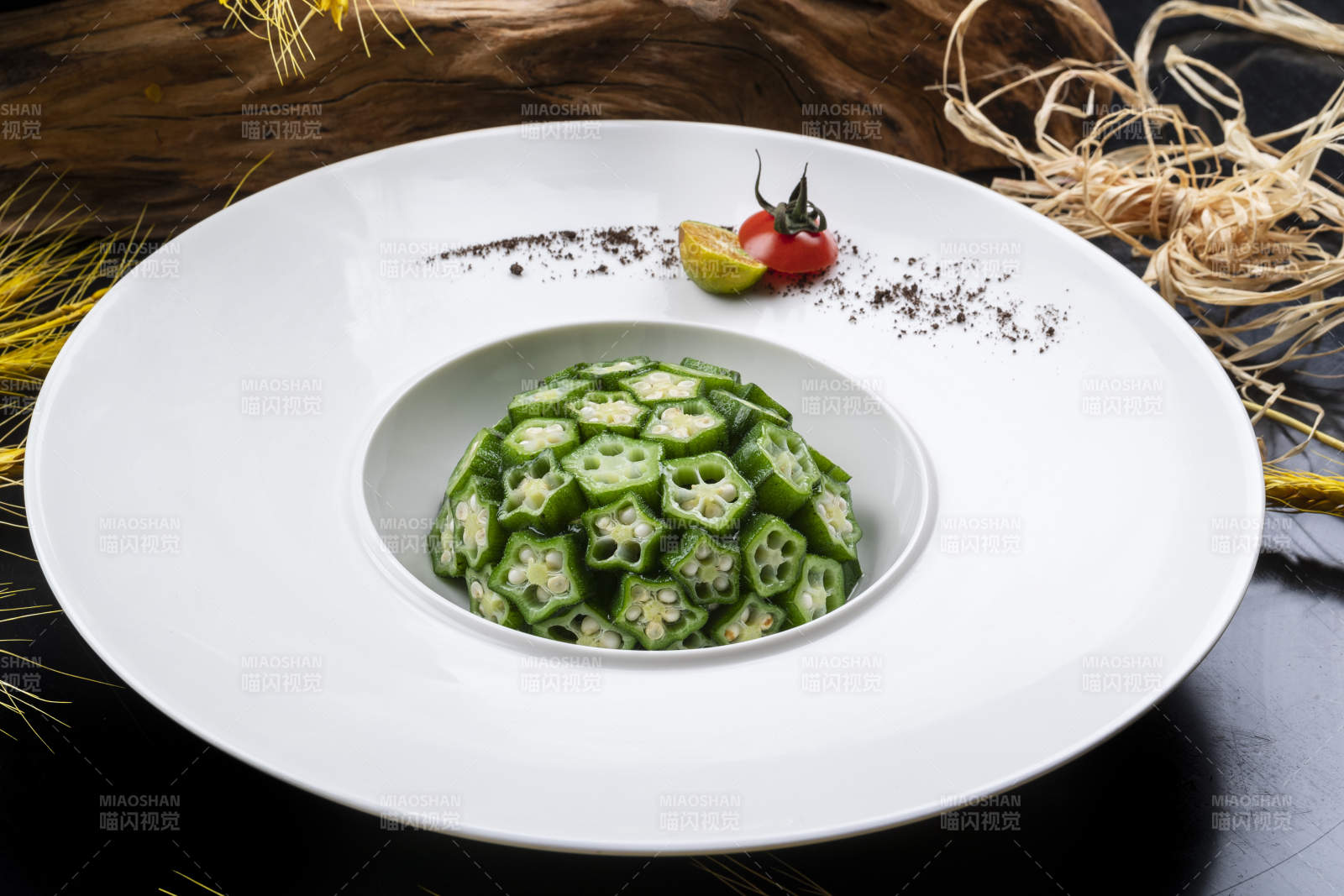 圆形瓷盘装的捞汁鲜秋葵摆放在黑色背景上图片