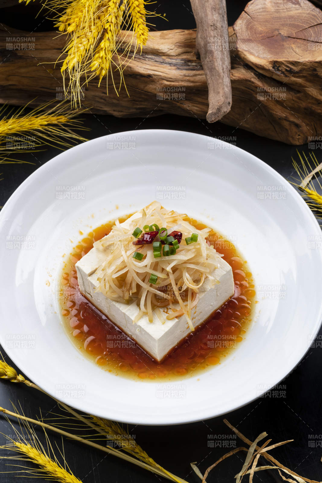 圆形瓷盘装的一品豆腐摆放在黑色背景上图片