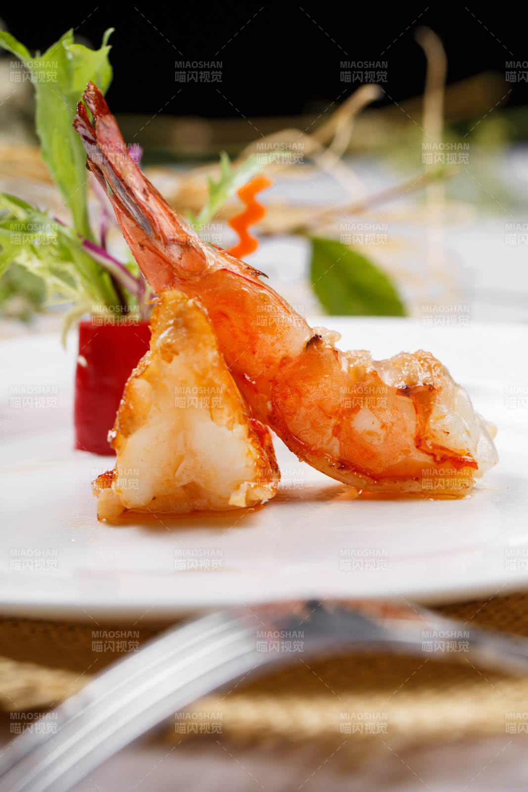 圆形白瓷盘装的铁板深海大明虾摆放在草垫上图片