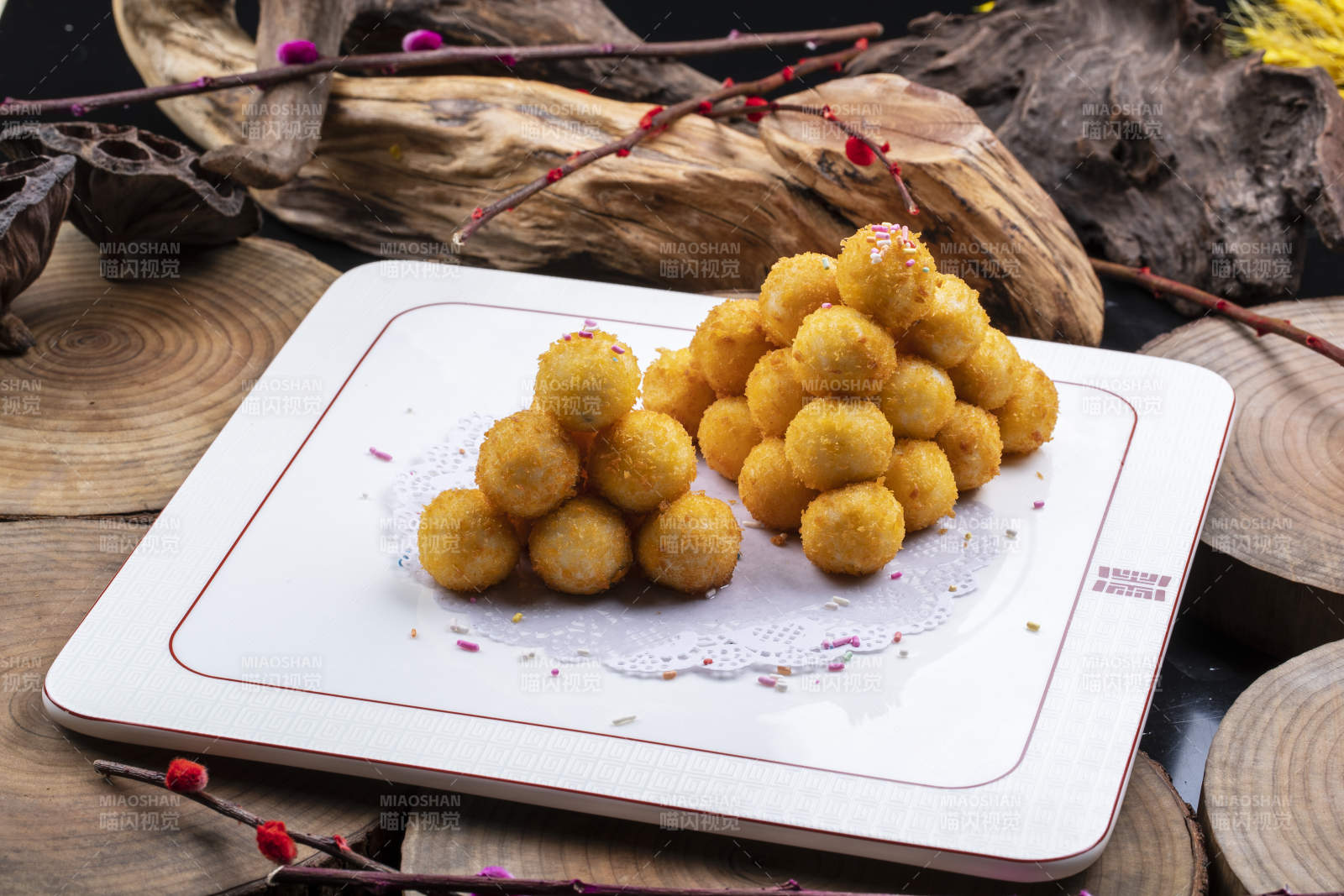 方形瓷盘装的黄金炸汤圆摆放在樟木砧板上图片