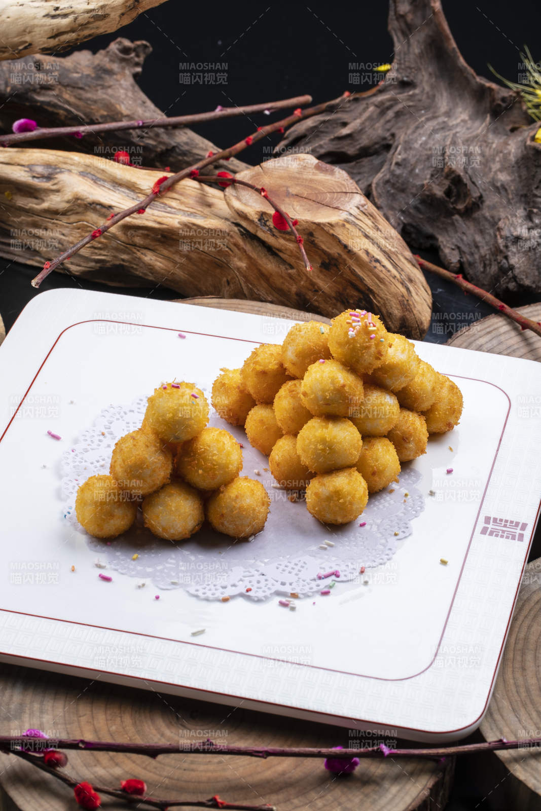 方形瓷盘装的黄金炸汤圆摆放在樟木砧板上图片