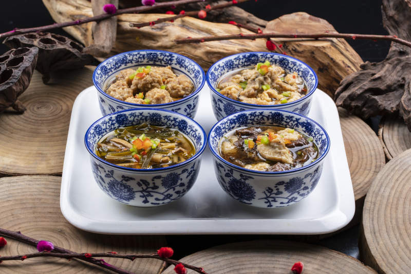 青花瓷碗装的传统四大碗摆放在樟木砧板上图片