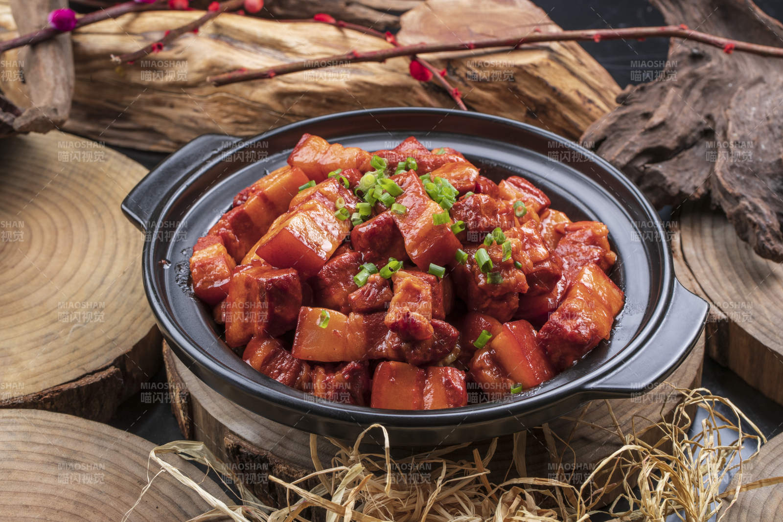 黑色砂锅装的锅仔红烧肉摆放在樟木砧板上图片