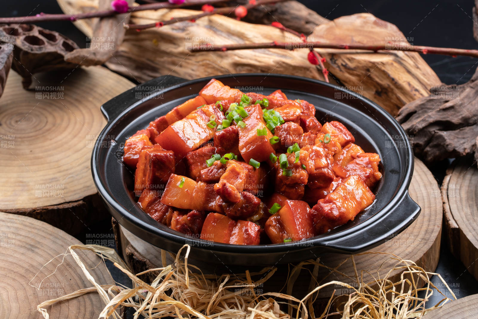 黑色砂锅装的锅仔红烧肉摆放在樟木砧板上图片