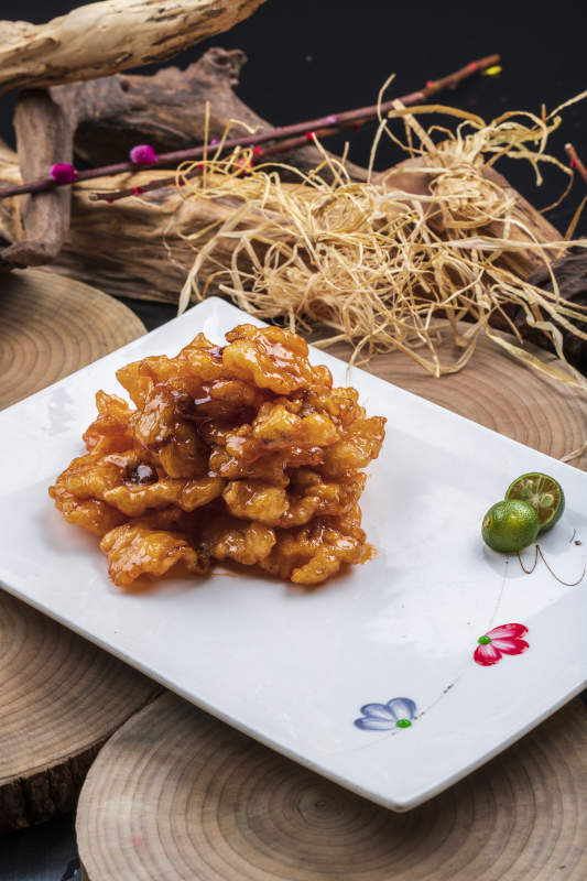 长方形瓷盘装的糖醋龙利鱼摆放在樟木砧板上图片