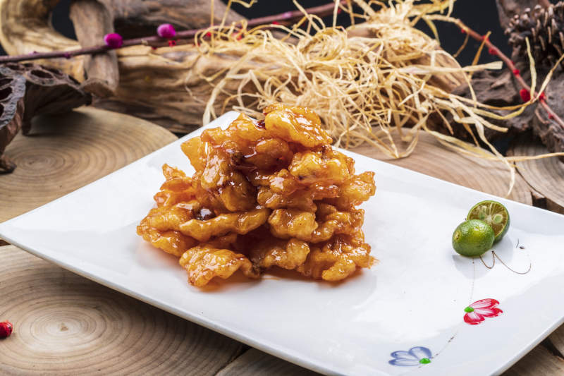 长方形瓷盘装的糖醋龙利鱼摆放在樟木砧板上图片