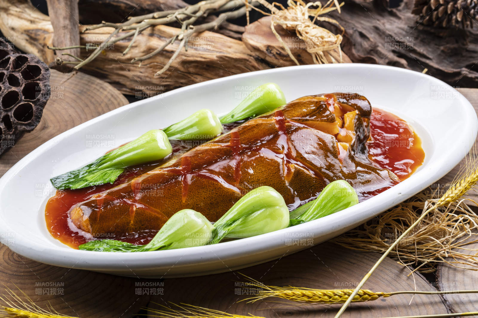 椭圆瓷盘装的红烧鲽鱼尾摆放在樟木砧板上图片