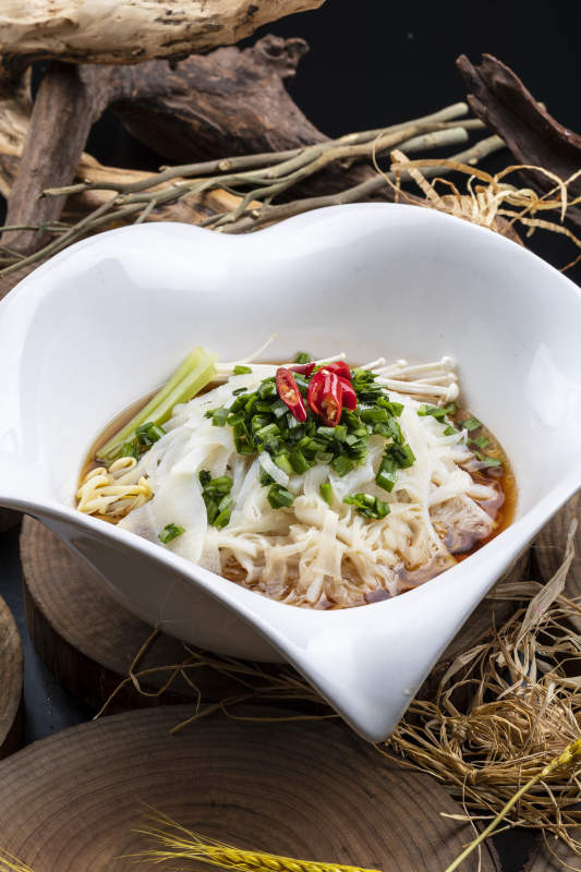 心型瓷盆装的晋味鸡汤凉皮摆放在樟木砧板上图片