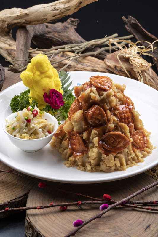 白色圆盘装的土豆焖鲍鱼摆放在樟木砧板上图片