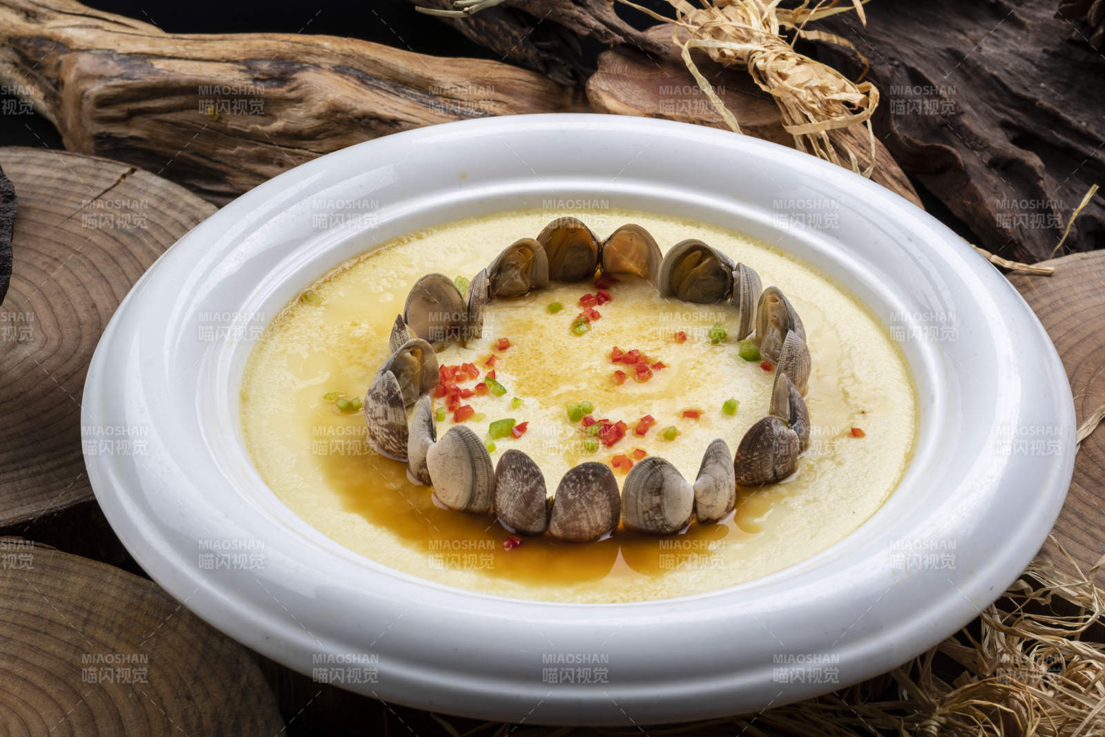 白色圆盘装的花蛤蒸蛋摆放在樟木砧板上图片