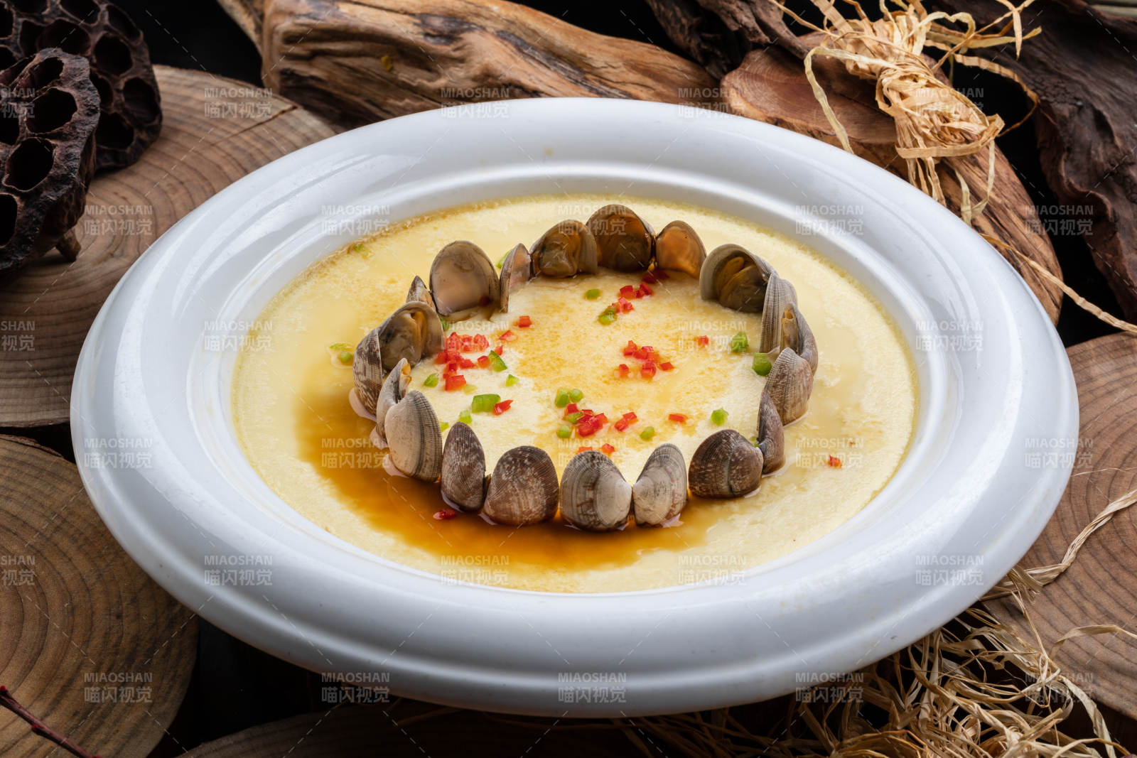 白色圆盘装的花蛤蒸蛋摆放在樟木砧板上图片