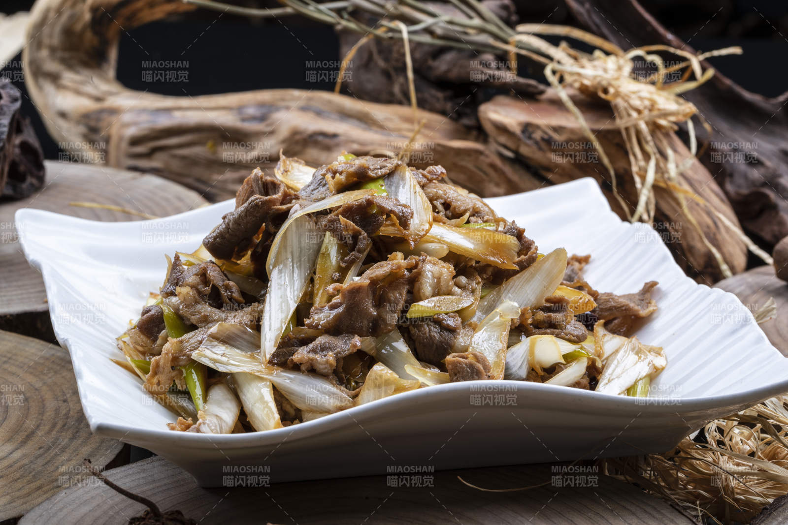 方形花瓷盘装的大葱爆羊肉摆放在樟木砧板上图片