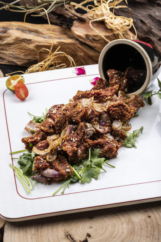 方形瓷盘装的孜然羊肉摆放在樟木砧板上图片