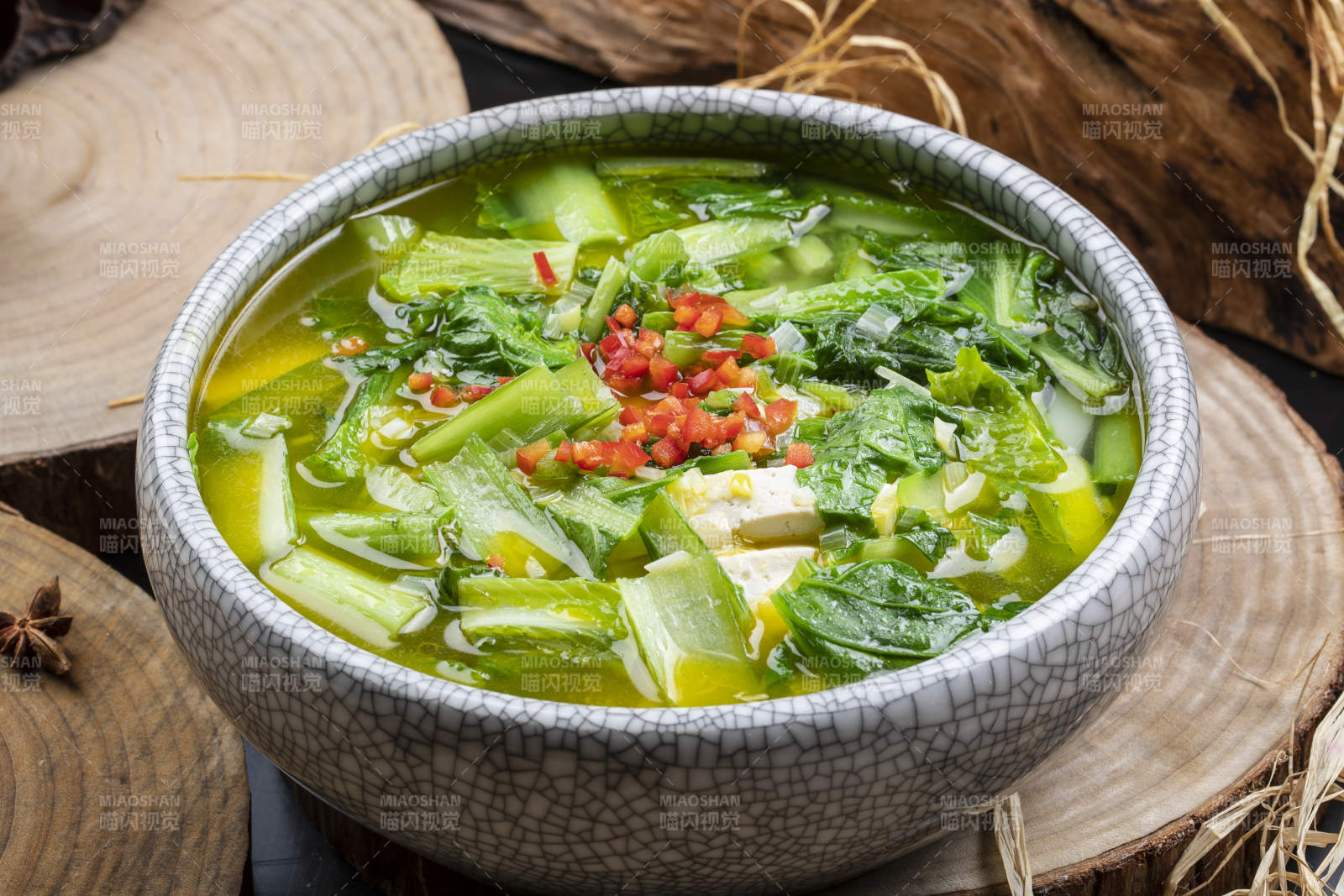 开片瓷碗装的小白菜烧豆腐摆放在樟木砧板上图片