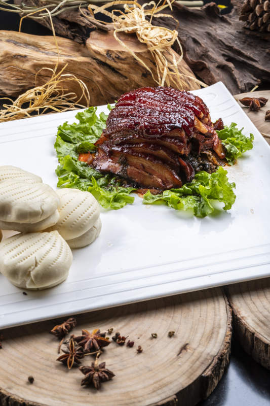 长方形瓷盘装的花馍夹酱肉摆放在樟木砧板上图片