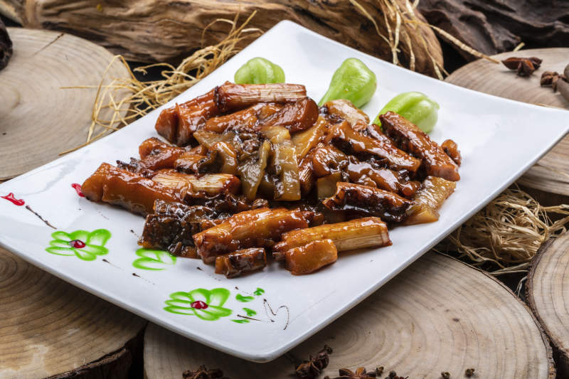 长方形花瓷盘装的葱烧皮参摆放在樟木砧板上图片