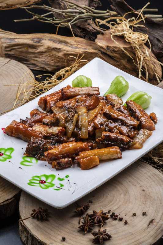 长方形花瓷盘装的葱烧皮参摆放在樟木砧板上图片