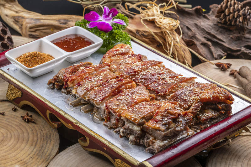 红色漆盘装的蒙古烤羊排摆放在樟木砧板上图片