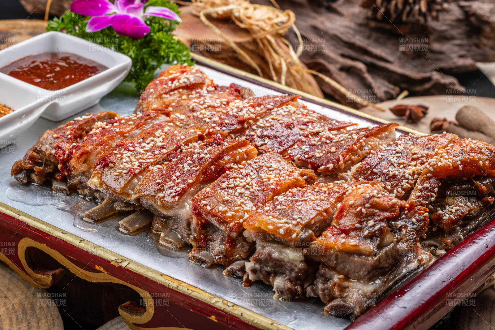 红色漆盘装的蒙古烤羊排摆放在樟木砧板上图片