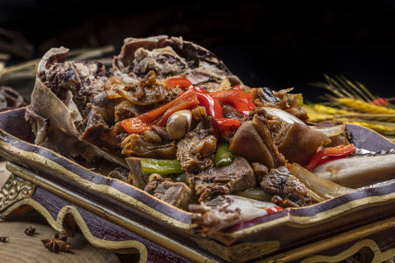 红漆木盘装的水煮蒜泥羊头摆放在樟木砧板上图片