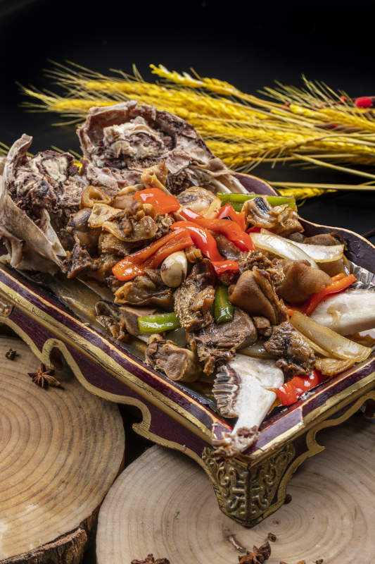 红漆木盘装的水煮蒜泥羊头摆放在樟木砧板上图片