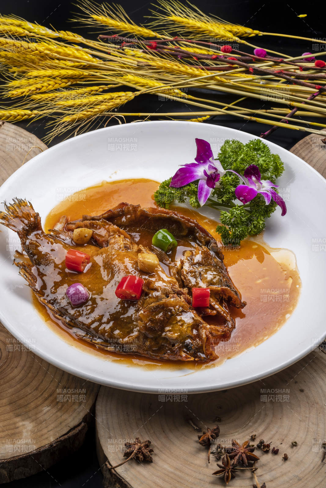 白色圆盘装的红烧罗非鱼摆放在樟木砧板上图片