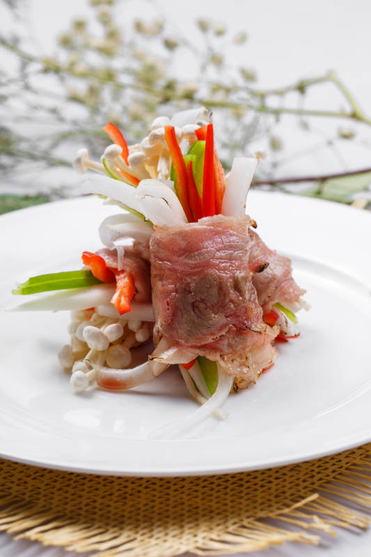 白色圆盘装的法式鹅肝牛肉卷摆放在草垫上图片