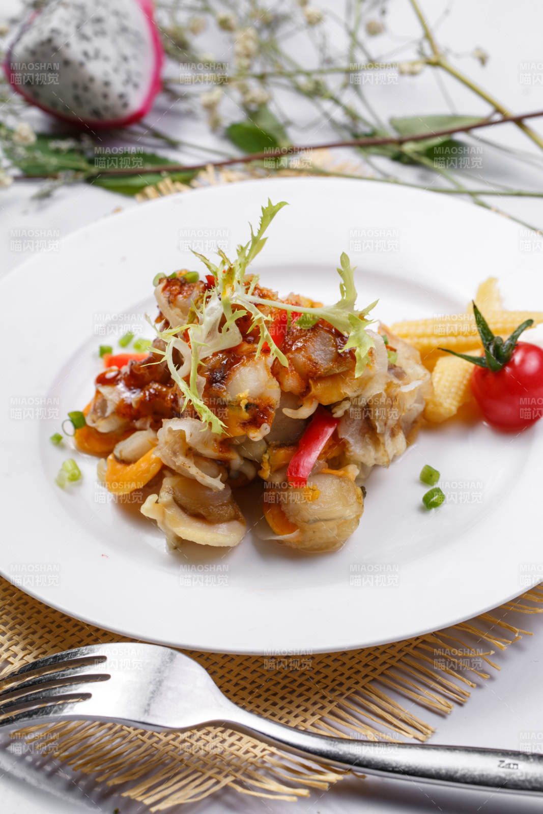 白色瓷盘装的铁板香辣扇贝肉摆放在草垫上图片