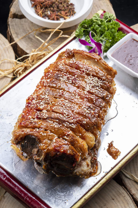 红漆木盘装的蒙古烤羊背摆放在樟木砧板上图片