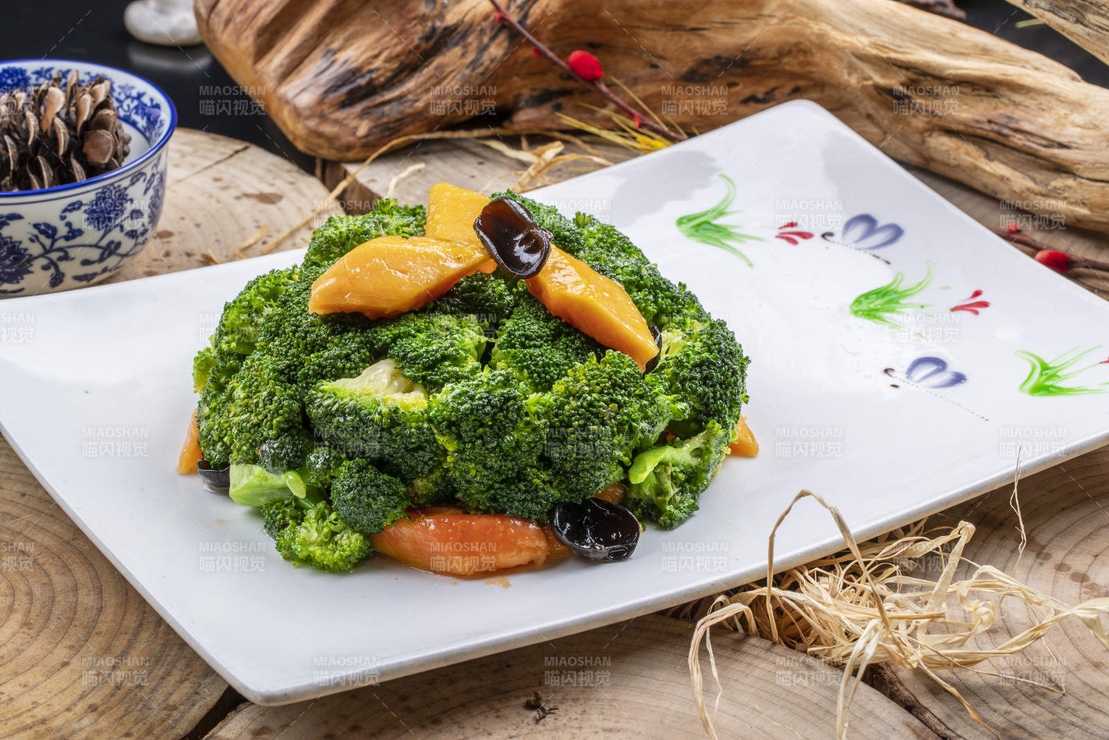 白色梅花瓷盘装的白灼西蓝花摆放在寿司帘上图片