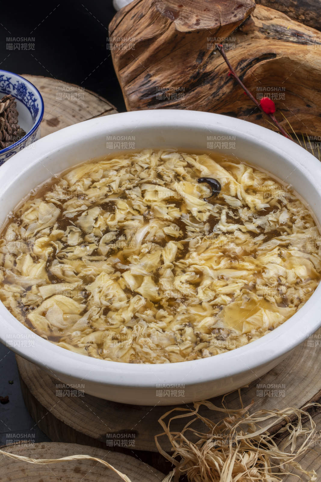 圆形汤盆装的酸辣汤摆放在木板上图片