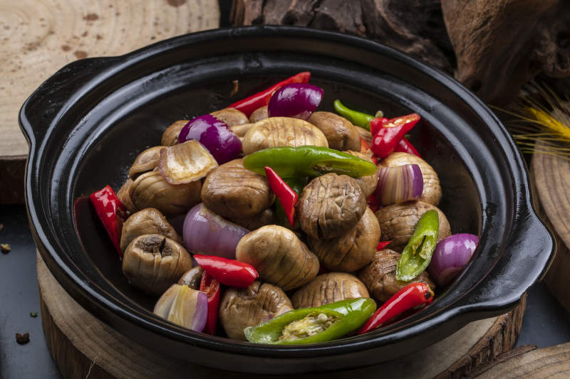 黑色砂锅装的小葱头鲜口蘑米椒煲图片