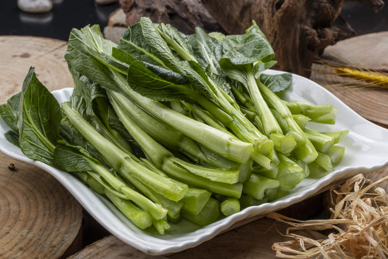 白色瓷盘装的生鲜新鲜菜心图片