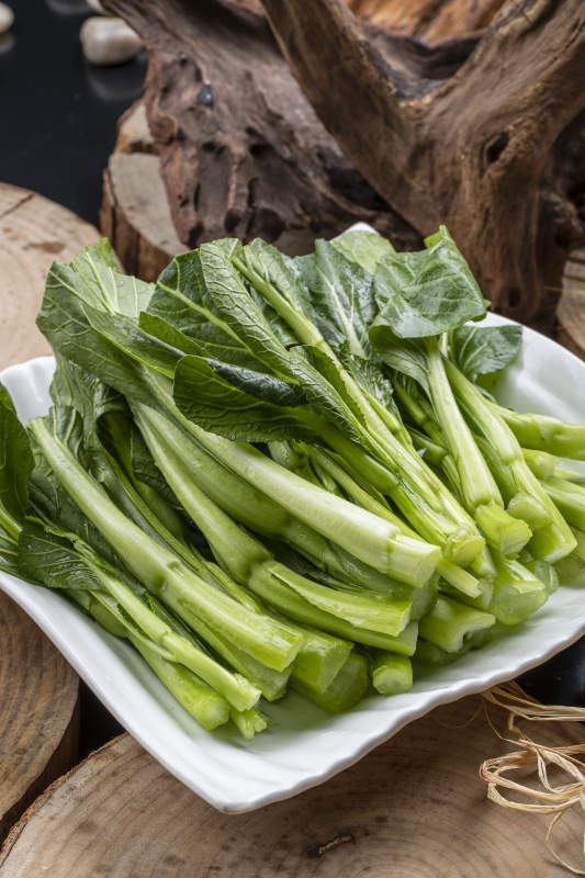 白色瓷盘装的生鲜新鲜菜心图片