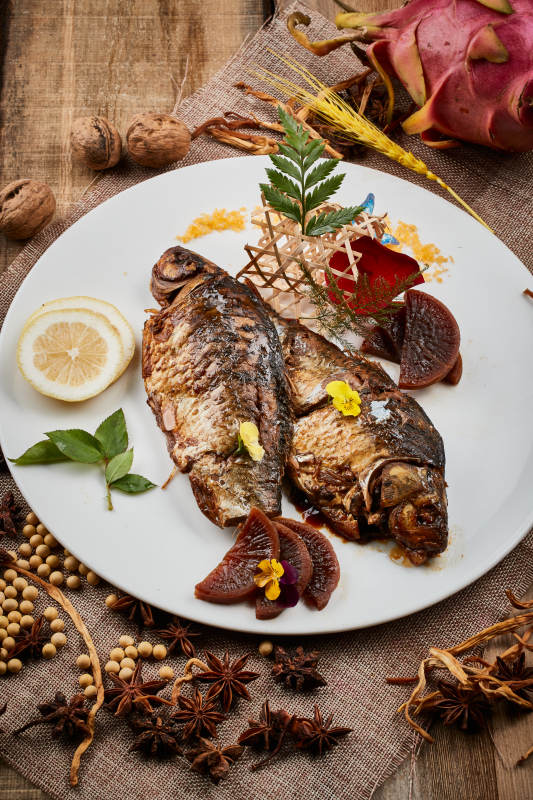 陈旧木板上的圆瓷盘装的家炖香酥鲫鱼图片