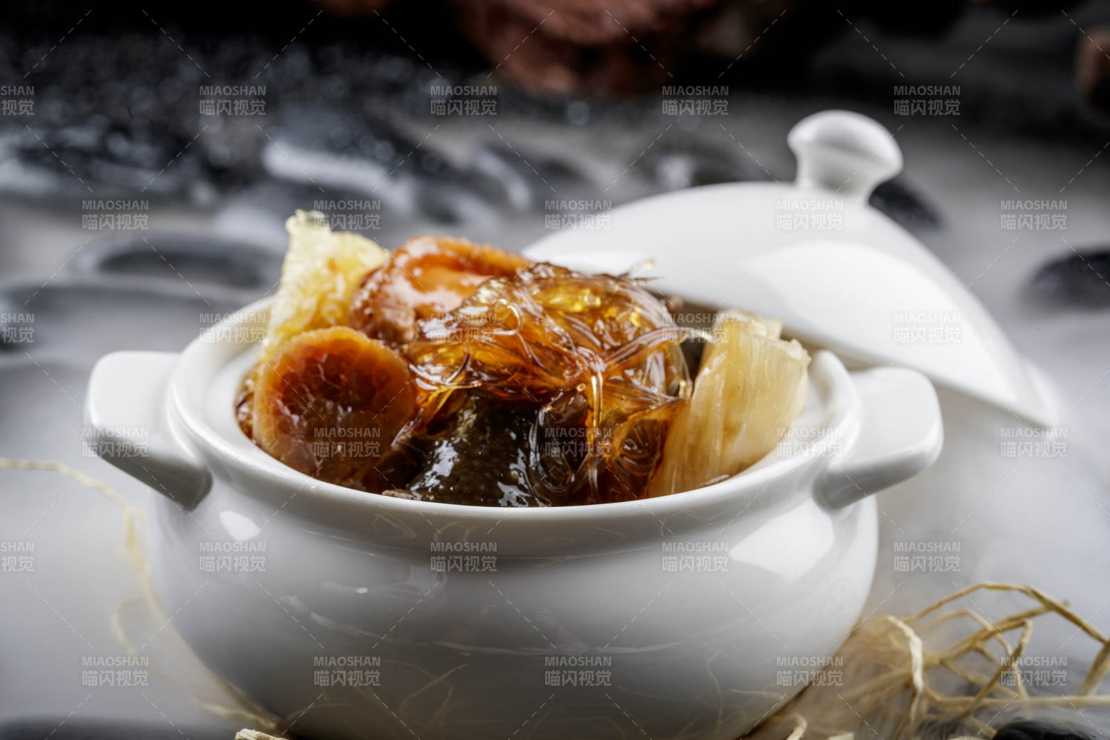 养生佛跳墙摆放在干冰缭绕的黑色鹅卵石山图片