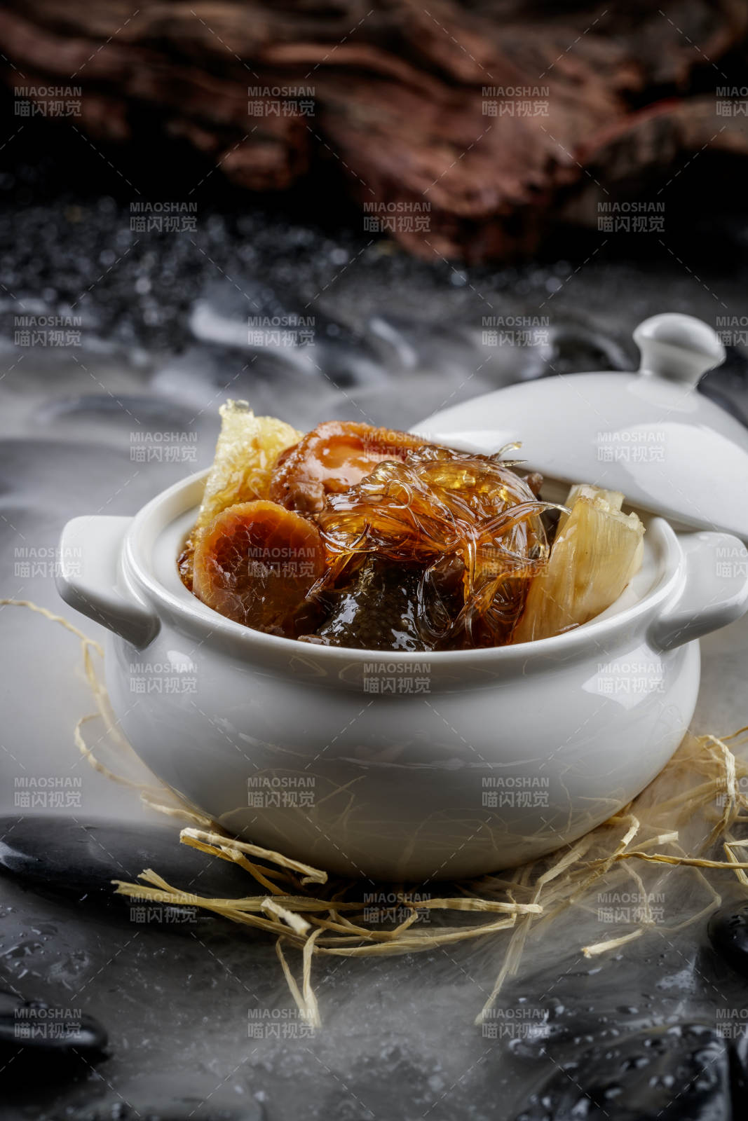 养生佛跳墙摆放在干冰缭绕的黑色鹅卵石山图片