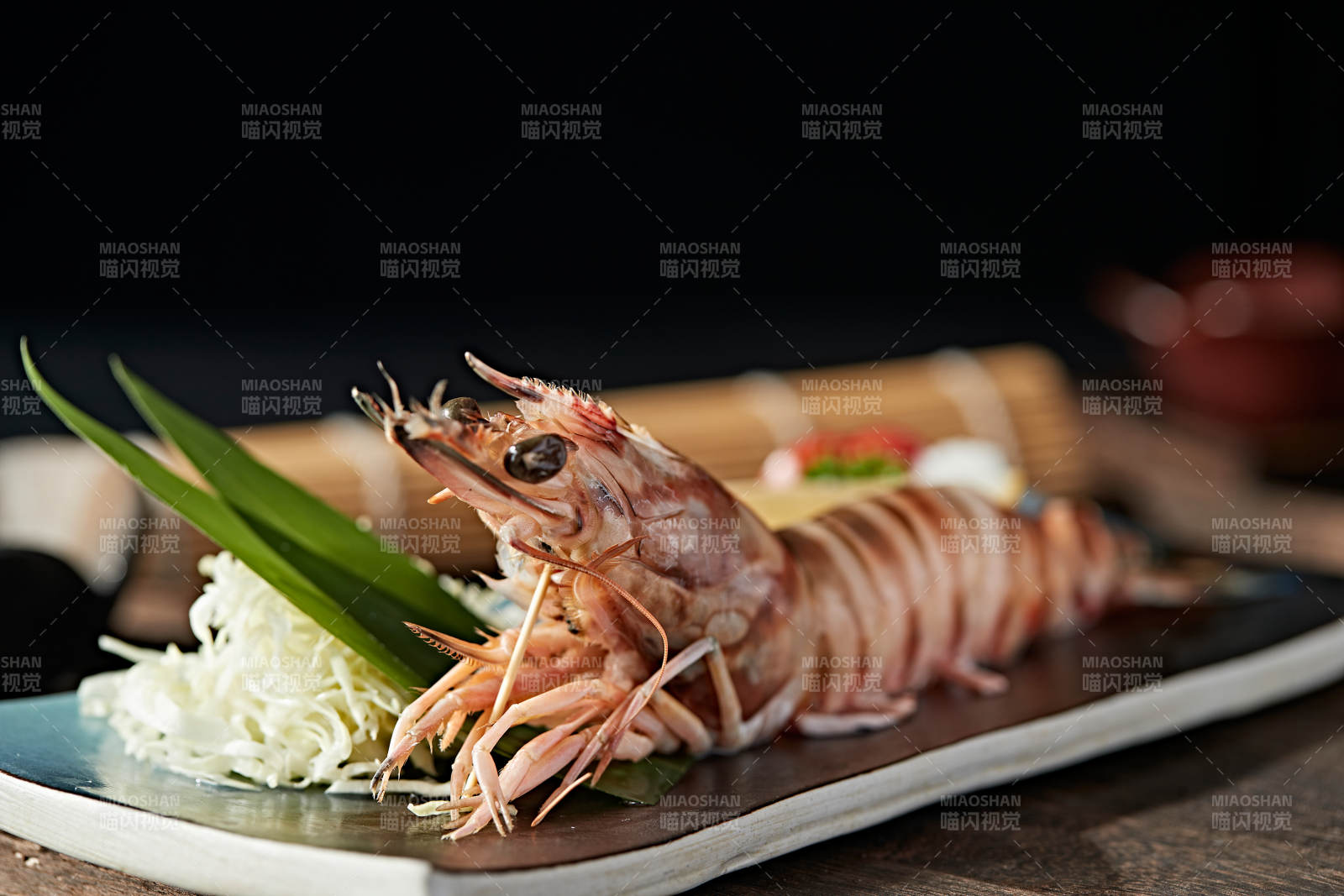 长方形瓷盘装的铁板野生明虾皇摆放在草垫上图片