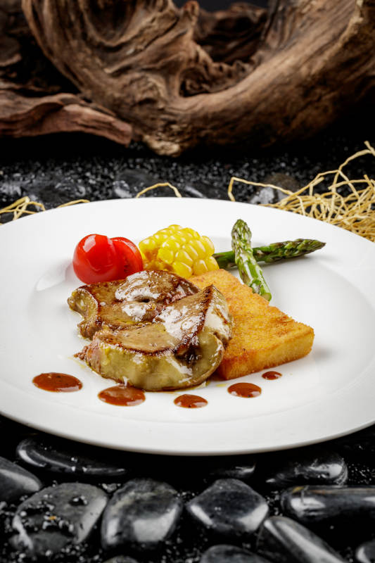 煎法式鹅肝摆放在黑色鹅卵石上图片