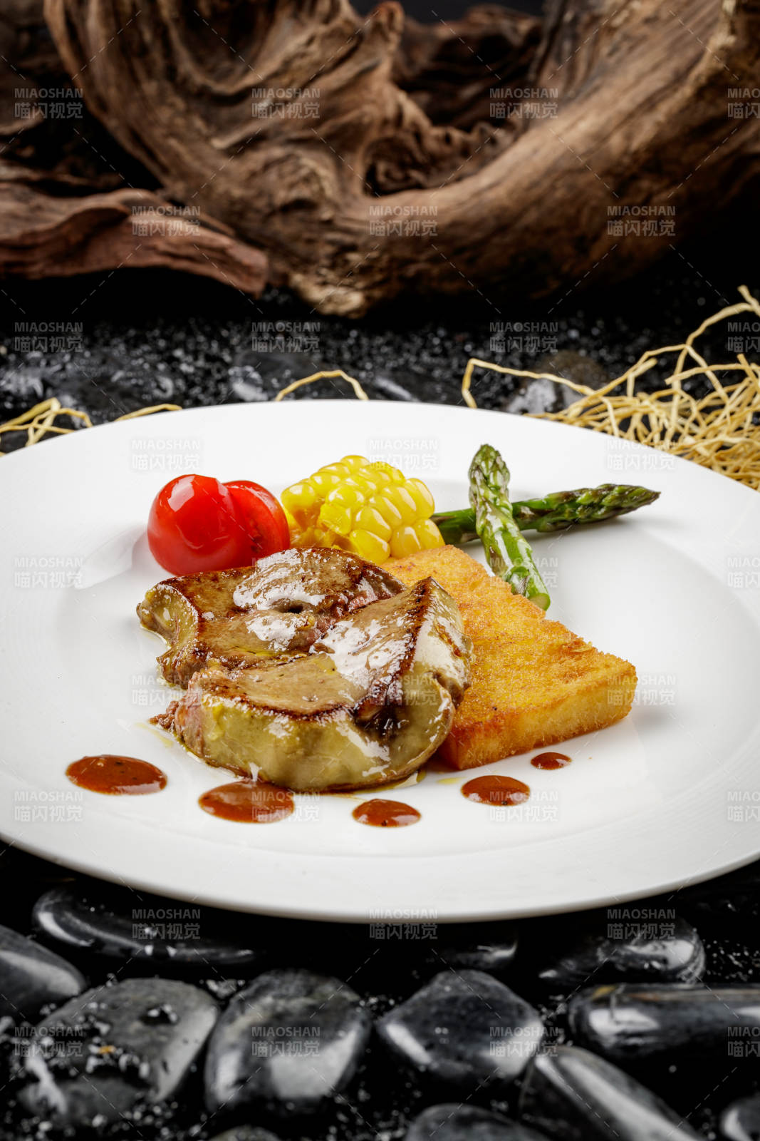 煎法式鹅肝摆放在黑色鹅卵石上图片
