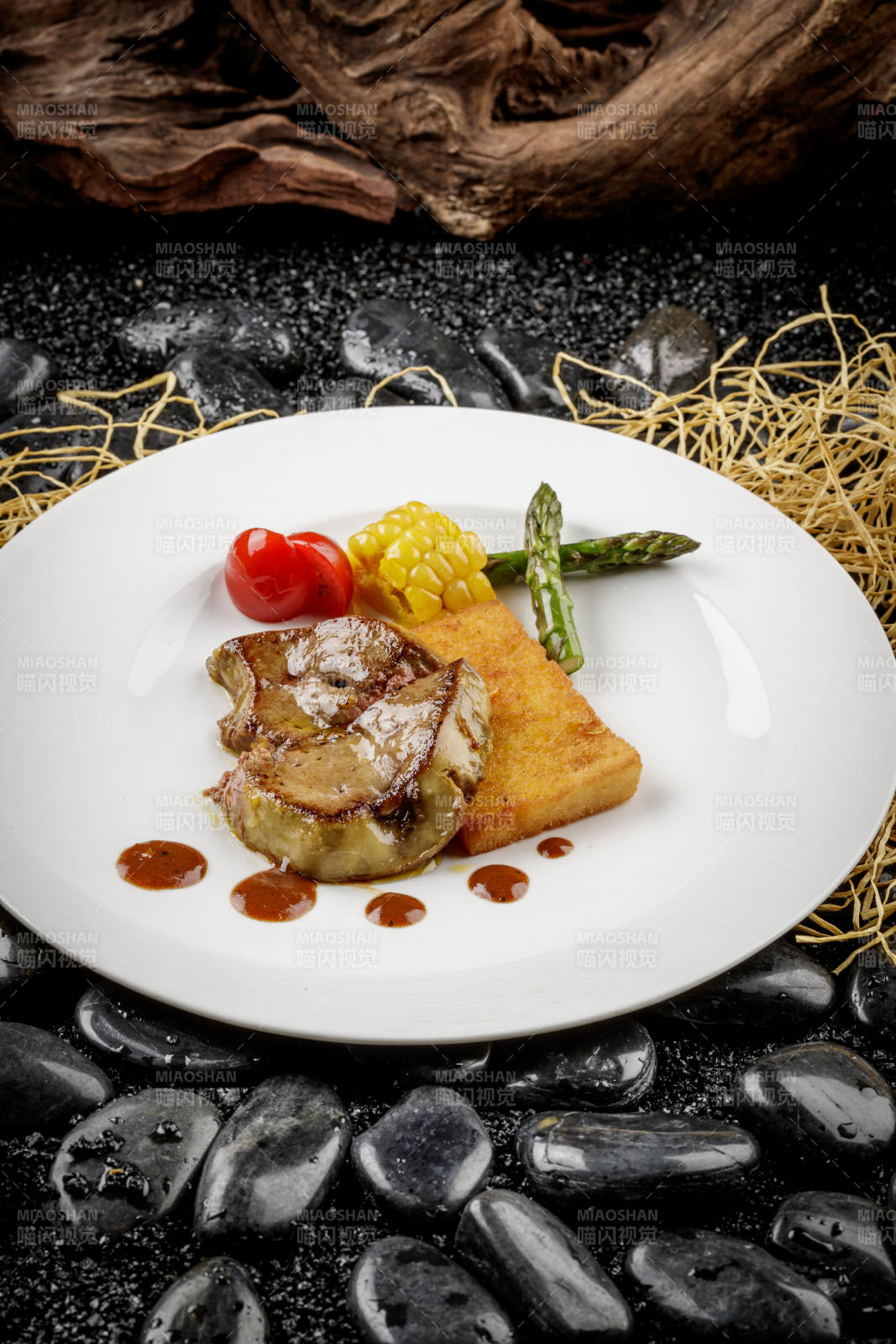 煎法式鹅肝摆放在黑色鹅卵石上图片