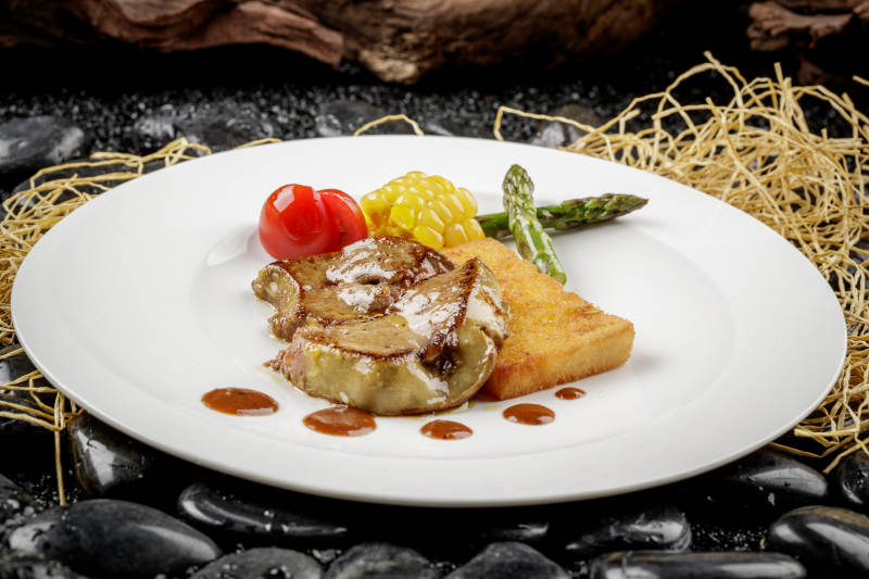 煎法式鹅肝摆放在黑色鹅卵石上图片