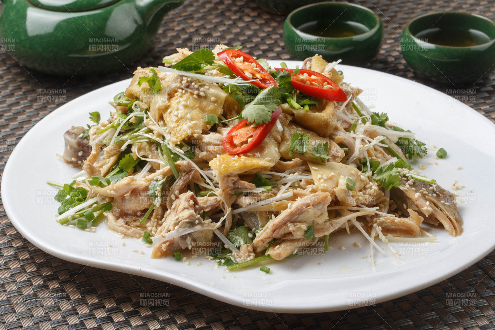 扇形白瓷盘装的麻辣手撕鸡摆放在餐垫上图片