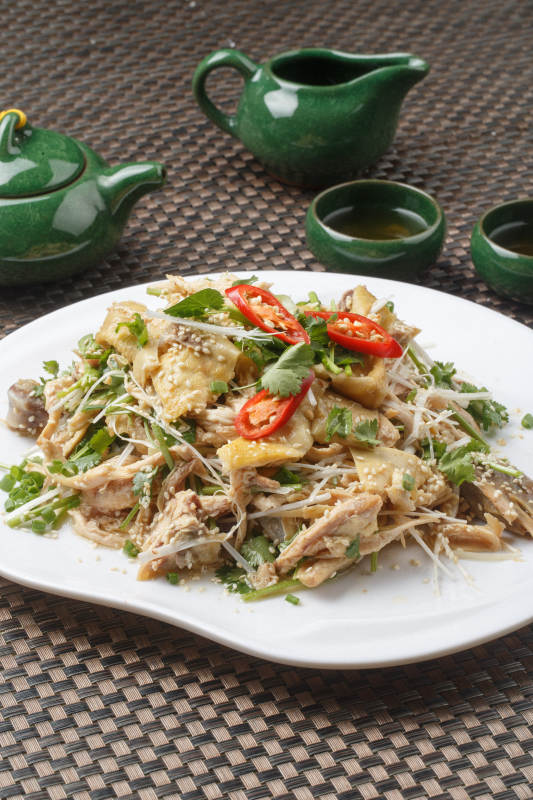 扇形白瓷盘装的麻辣手撕鸡摆放在餐垫上图片