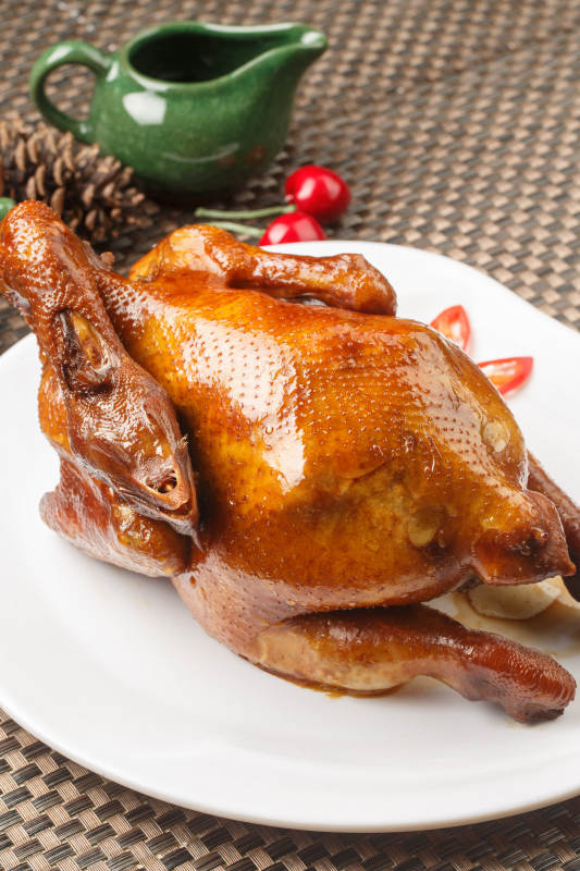 白色圆瓷盘装的港式脆皮鸡摆放在餐垫上图片