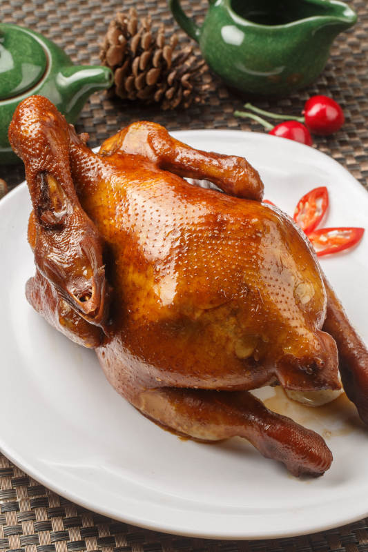 白色圆瓷盘装的港式脆皮鸡摆放在餐垫上图片