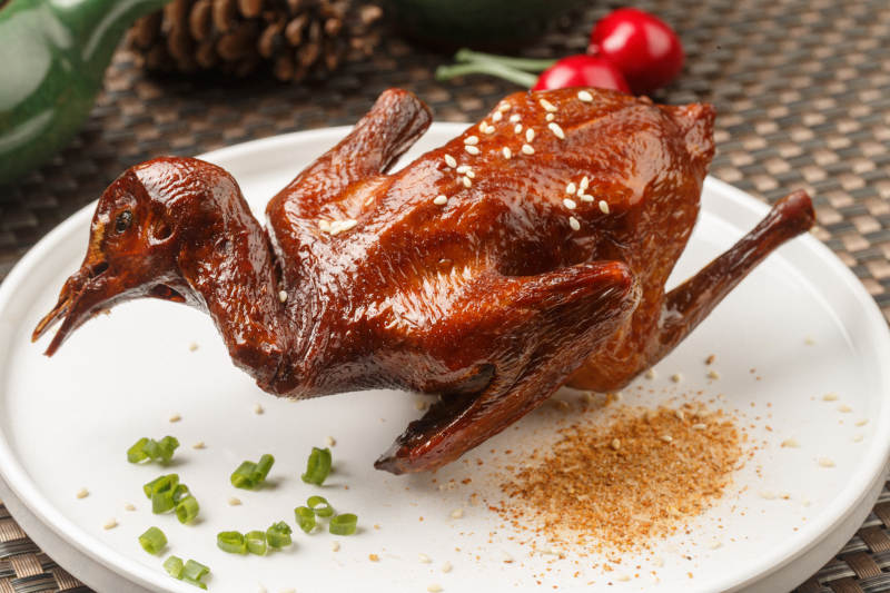 圆形白瓷盘装的港式脆皮乳鸽摆放在餐垫上图片