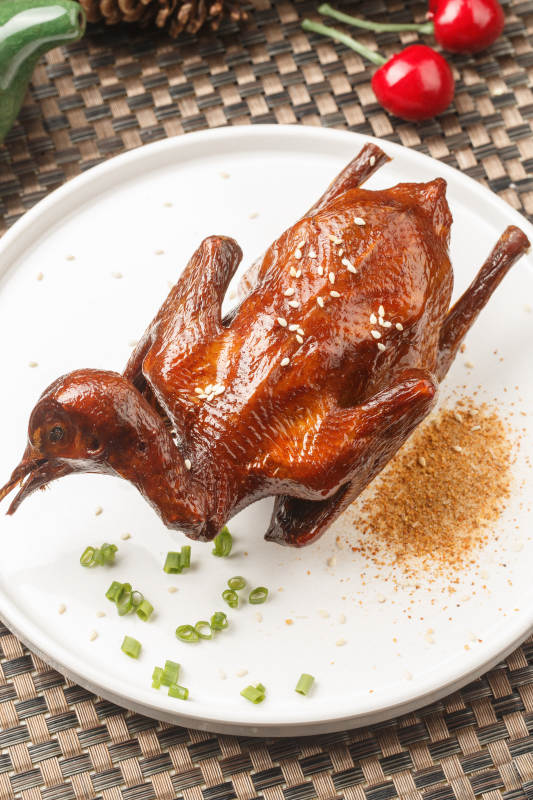 圆形白瓷盘装的港式脆皮乳鸽摆放在餐垫上图片